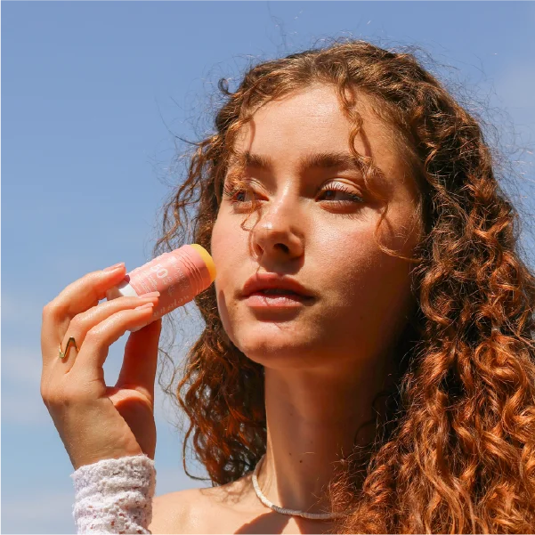 Jeune femme à la plage appliquant un stick solaire visage SPF50 pour une protection optimale contre les UV