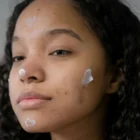 Femme appliquant la crème hydra-apaisante anti-imperfections bio sur les rougeurs de son visage