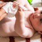 Bébé tenant une lingette à l’eau dans sa main pendant le change.