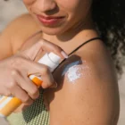 Application spray solaire minéral haute protection sur la peau visage et corps. Crème solaire bio application sur le corps.